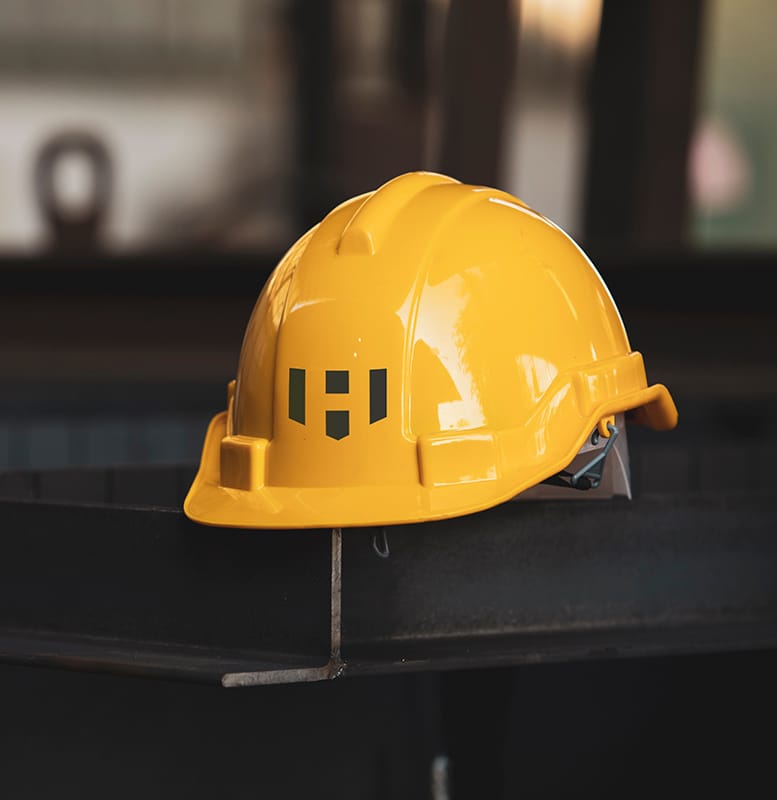 Yellow safety helmet on steel structure at construction site,yel Hire Elite branded hard hat